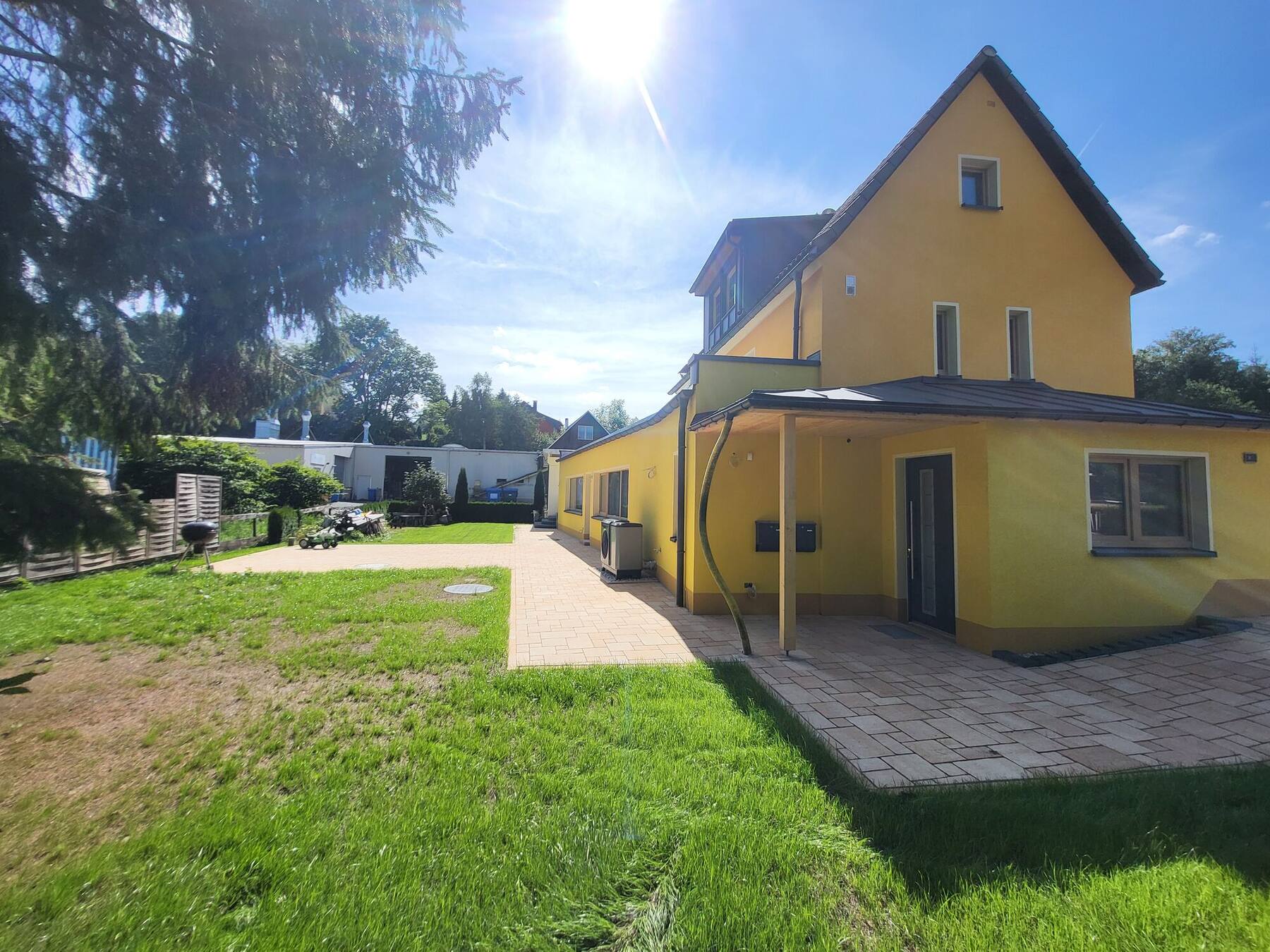 Das gelb gestrichene Haus in Mulda an einem sonnigen Tag, rechts der Giebel des Fachwerkhauses