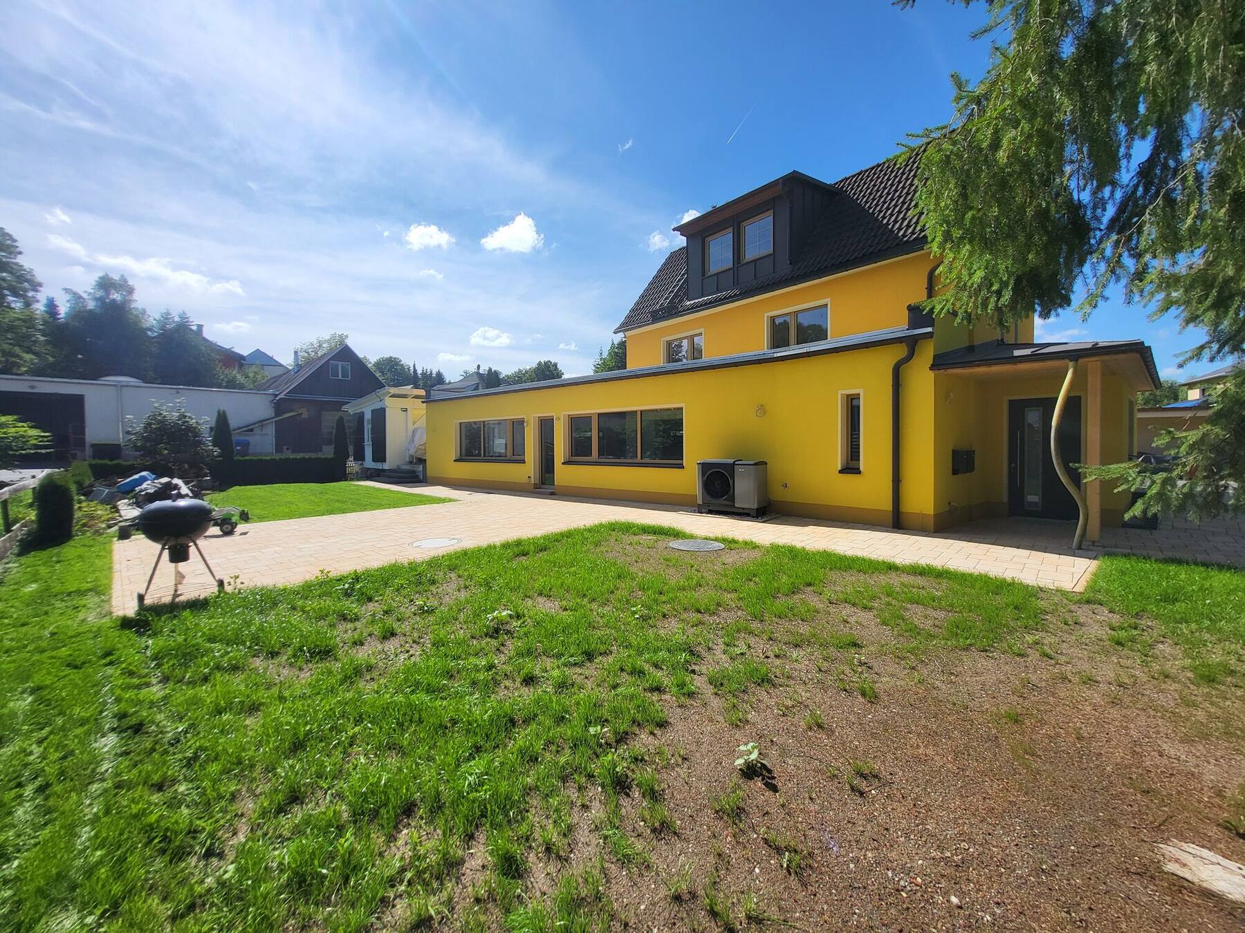 Das gelbe Haus mit großem Garten unter blauem Himmel
