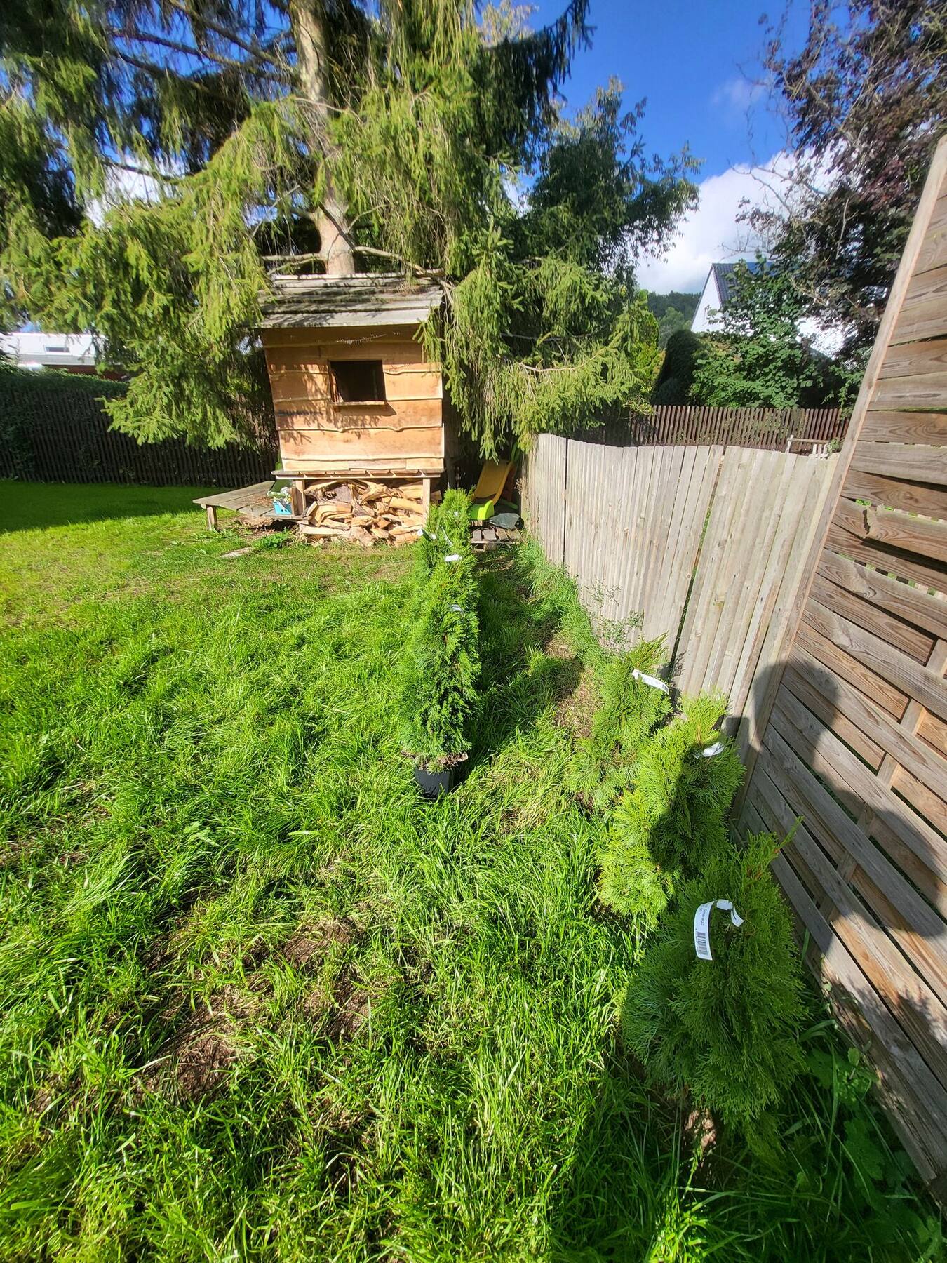 Kinder-Holzspielhaus im Garten unter großen Bäumen